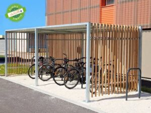 Abri vélo design en bois et métal avec plusieurs vélos stationnés, situé près d’un bâtiment.