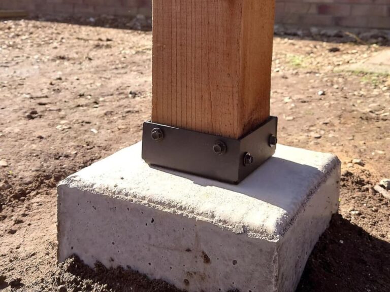 Poteau en bois fixé sur une base en béton avec une équerre métallique noire.