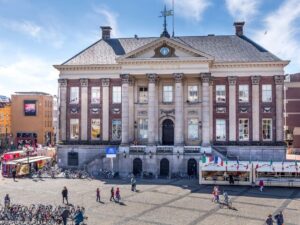 Façade d'un bâtiment historique avec vélos stationnés sur une place animée.